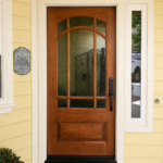 Beautiful craftsman-style front door featuring decorative glass and a custom warm wood stain by Paintmasters.