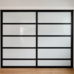 A sleek modern sliding door with frosted glass panels and a bold black frame—professionally finished by Paintmasters.