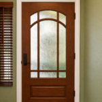 Beautiful craftsman-style front door featuring decorative glass and a custom warm wood stain by Paintmasters.